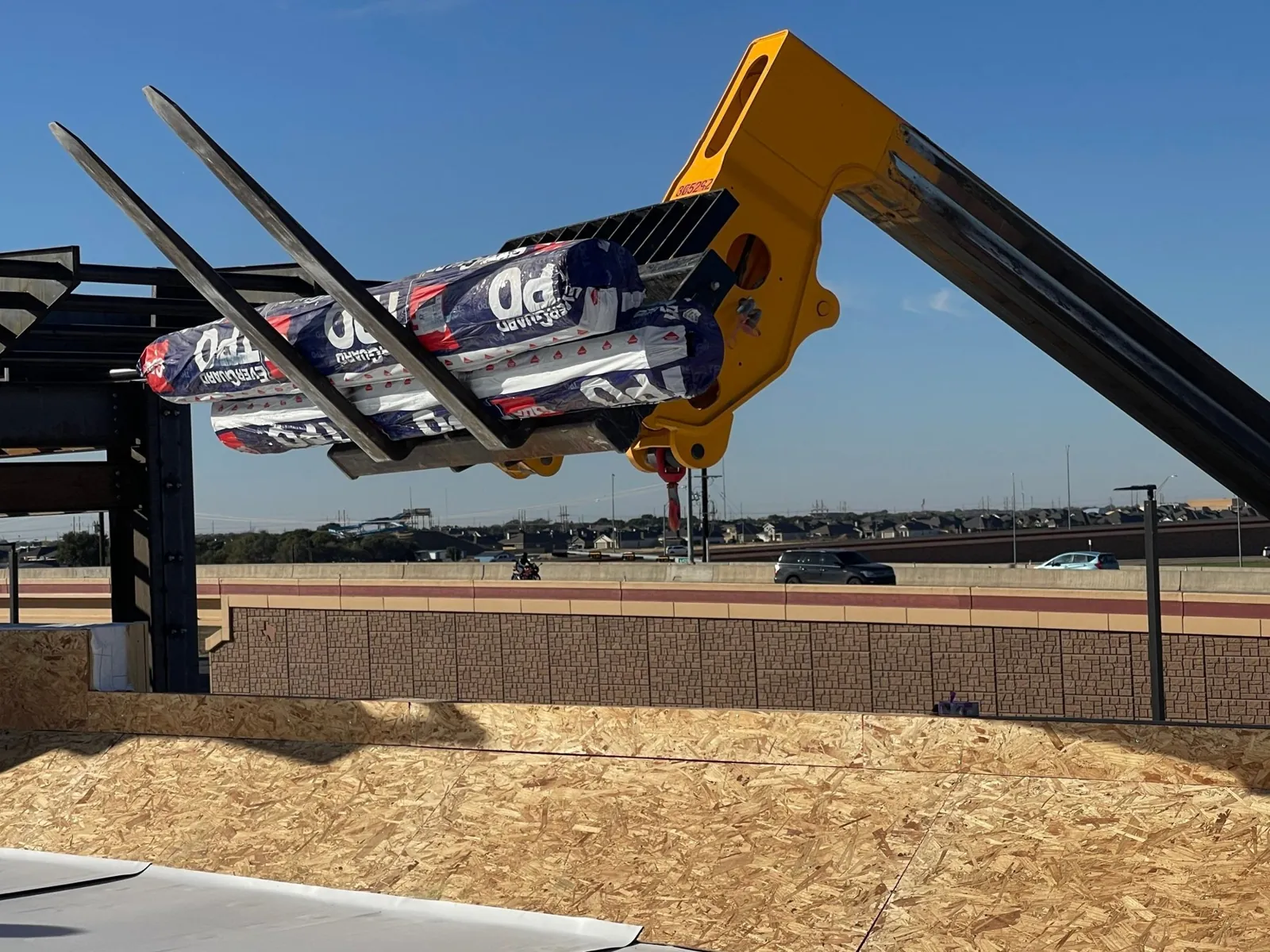 Telehandler staging TPO rolls to the roof