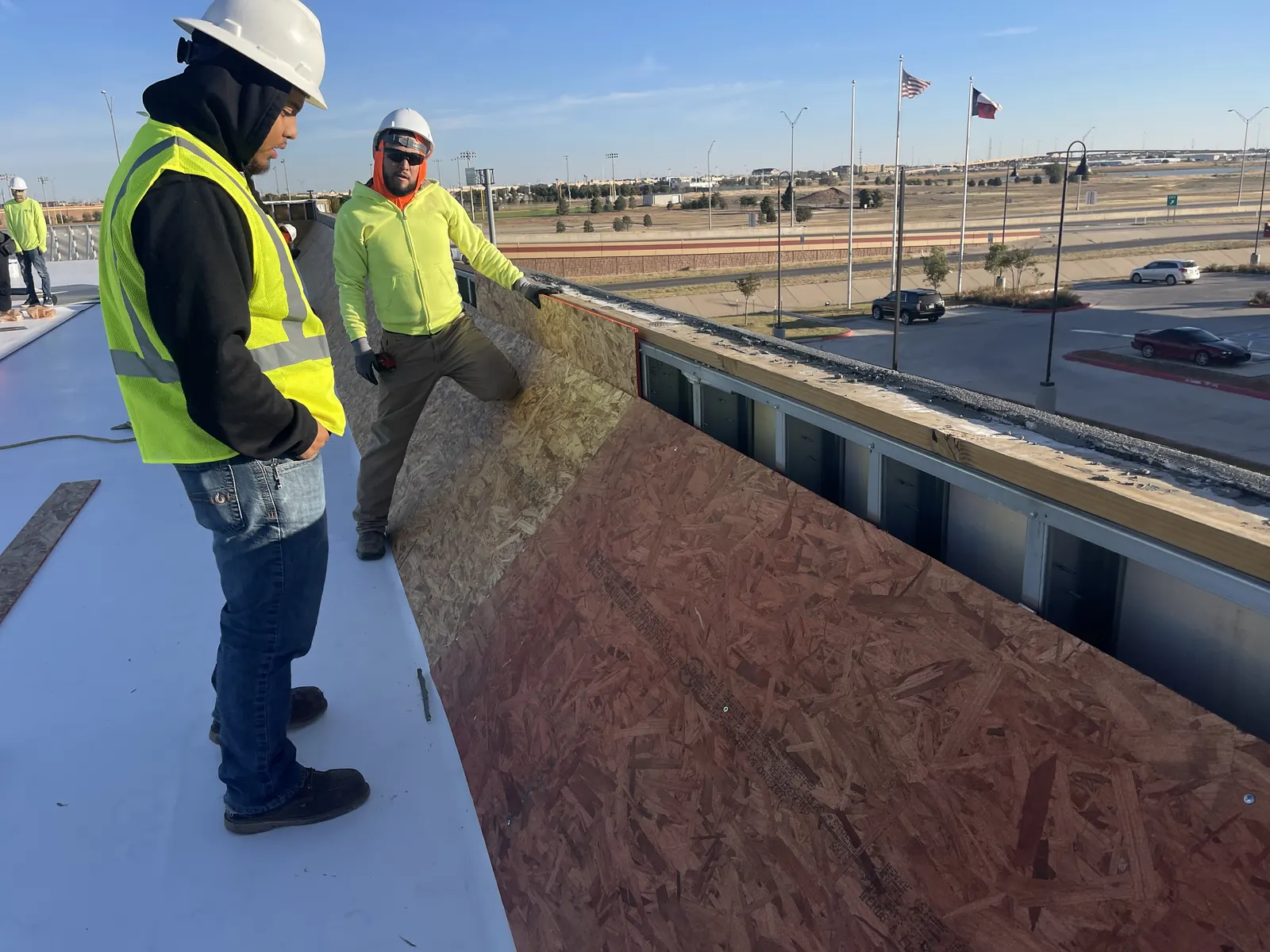 Revolver Roofing crew members in hard hats on a commercial roof