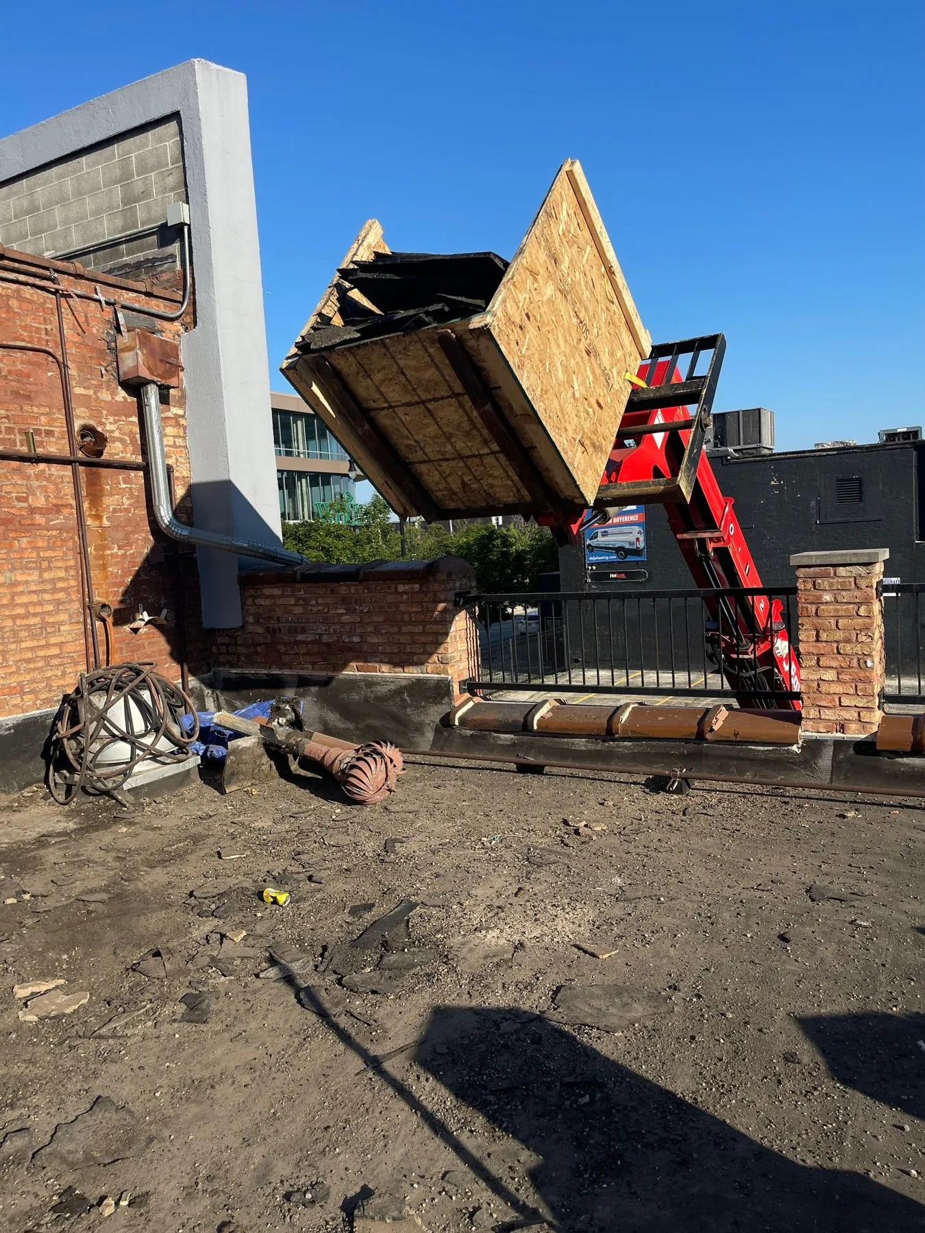 Telehandler lifting materials over the parapet from the valet lot