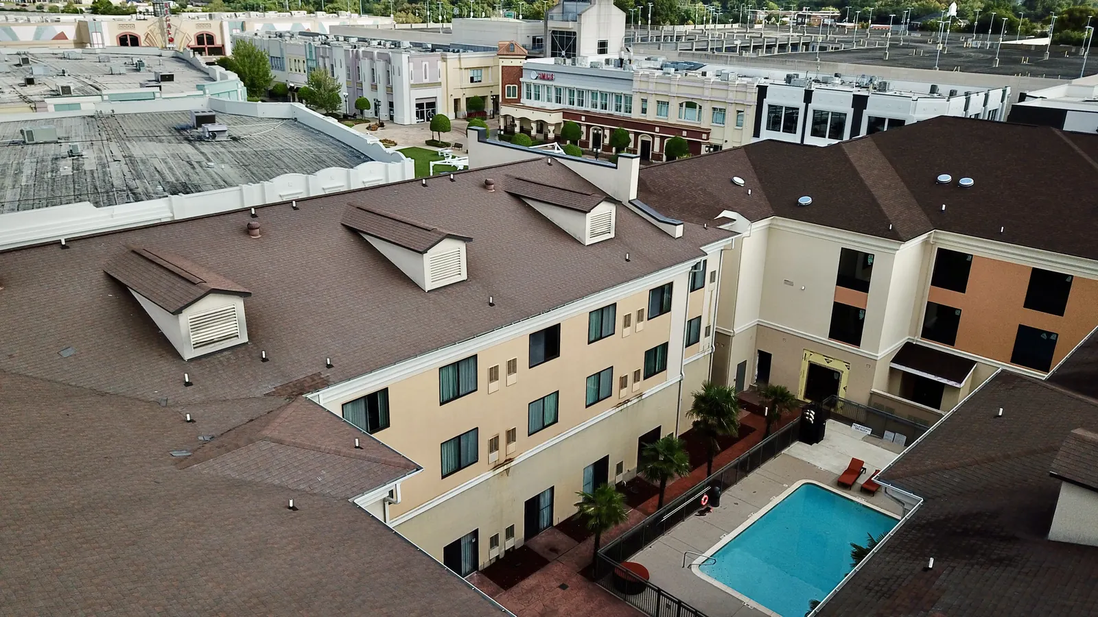 Commercial architectural shingle re-roof on a three-story hotel with dormers and courtyard pool